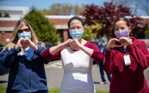 multi-generational team of nurses in healthcare - three nurses with hands in shape of heart
